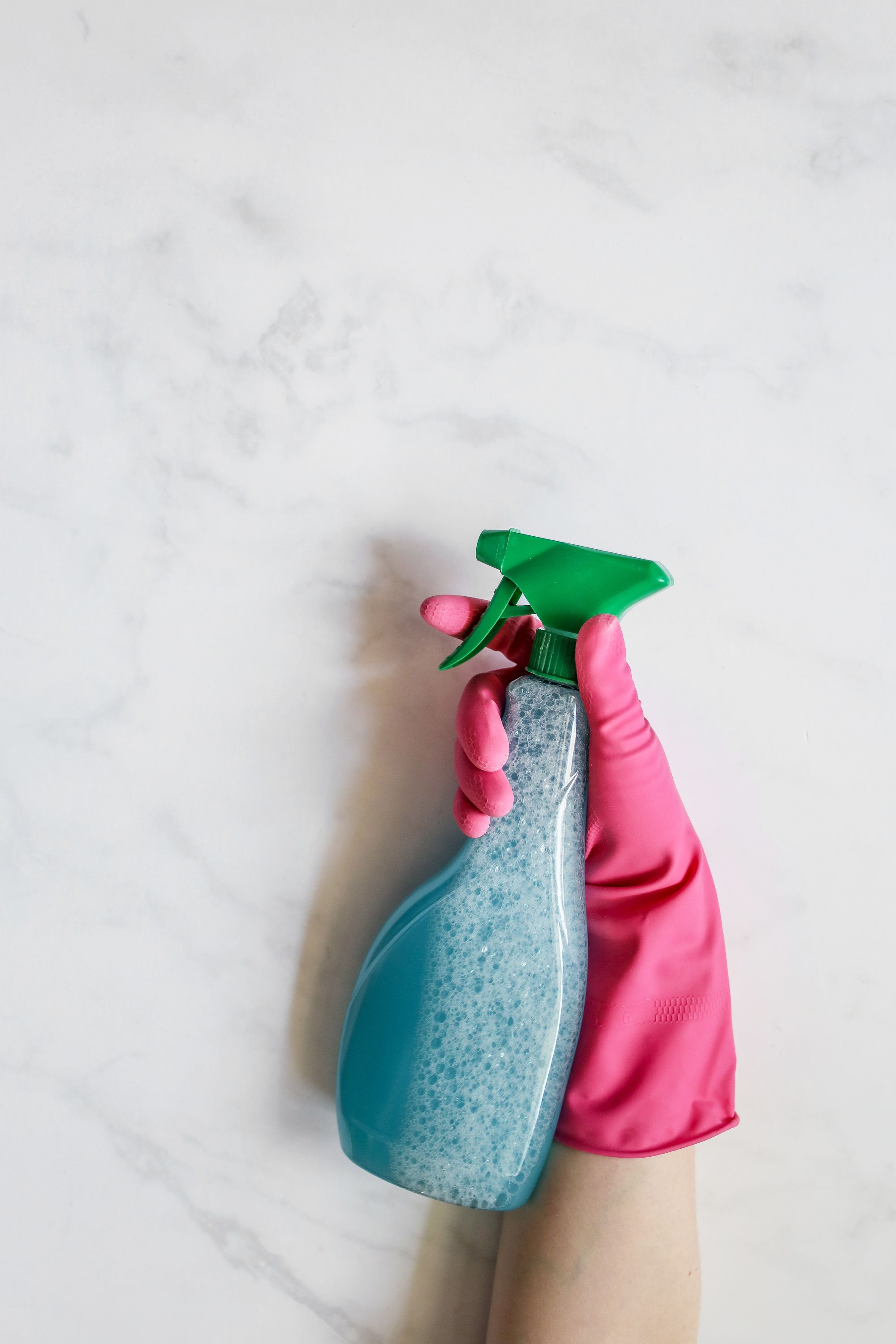A spray bottle held against a clean pale surface